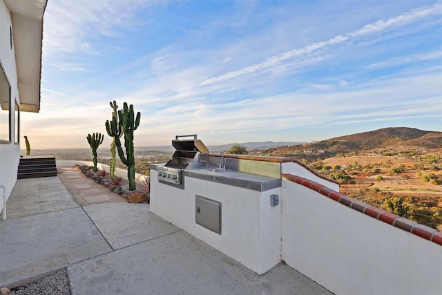 view of patio with exterior kitchen, a mountain view, and a grill