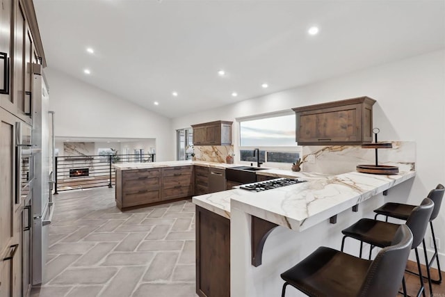 kitchen featuring lofted ceiling, sink, a breakfast bar area, gas cooktop, and kitchen peninsula