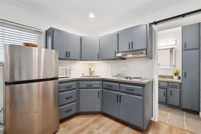 kitchen with gray cabinetry, sink, decorative backsplash, and stainless steel fridge