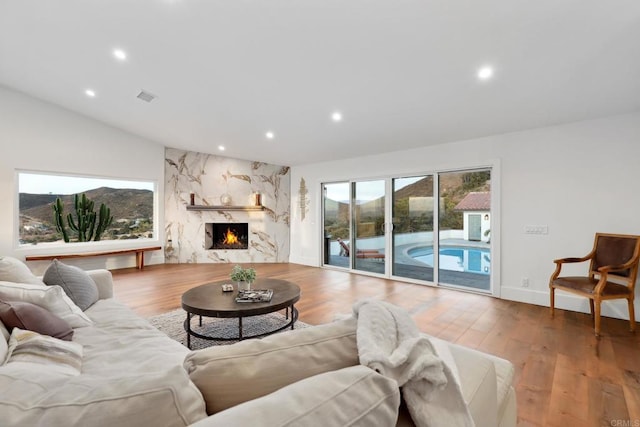 living room with lofted ceiling, a high end fireplace, and light hardwood / wood-style floors