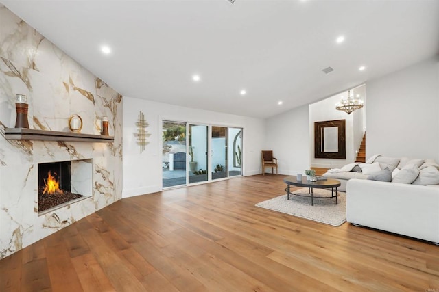 unfurnished living room featuring wood-type flooring, a large fireplace, and a chandelier