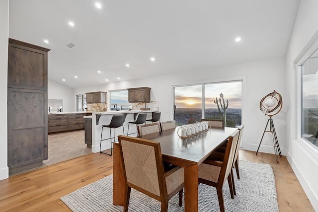 dining area with lofted ceiling and light hardwood / wood-style floors