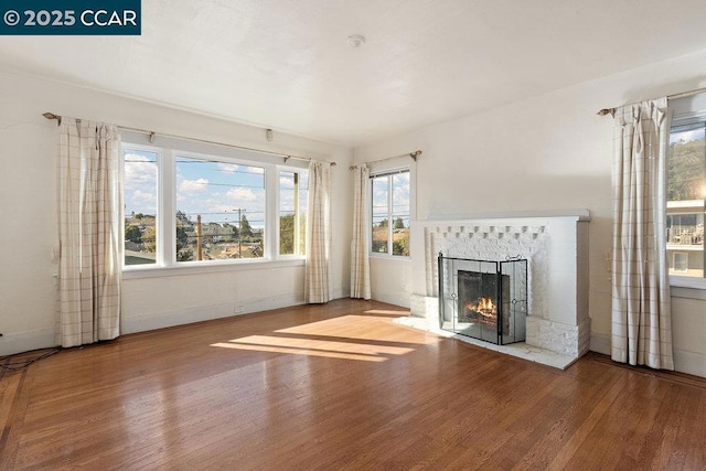 unfurnished living room featuring hardwood / wood-style flooring and a tiled fireplace