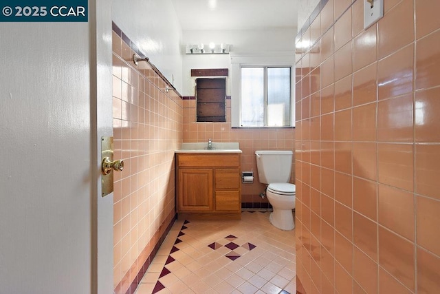 bathroom featuring tile walls, vanity, tile patterned flooring, and toilet