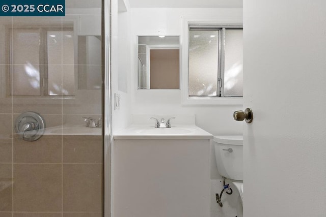 bathroom with toilet, vanity, and a shower with shower door