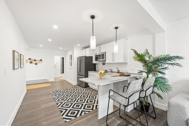 kitchen with white cabinetry, a baseboard radiator, appliances with stainless steel finishes, kitchen peninsula, and pendant lighting