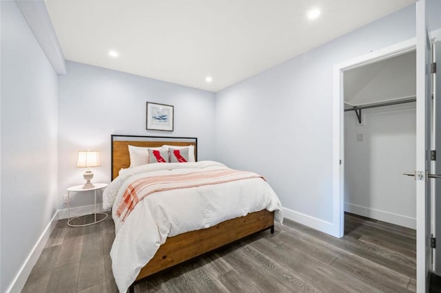 bedroom with a walk in closet, dark hardwood / wood-style floors, and a closet