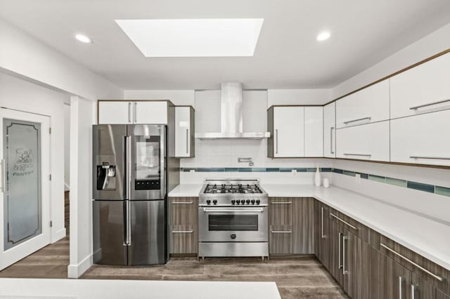 kitchen featuring dark wood-type flooring, white cabinetry, dark brown cabinets, stainless steel appliances, and wall chimney exhaust hood