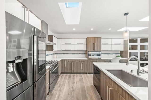 kitchen featuring pendant lighting, tasteful backsplash, sink, white cabinets, and stainless steel appliances