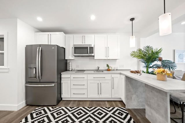 kitchen with hanging light fixtures, appliances with stainless steel finishes, white cabinets, and a kitchen breakfast bar