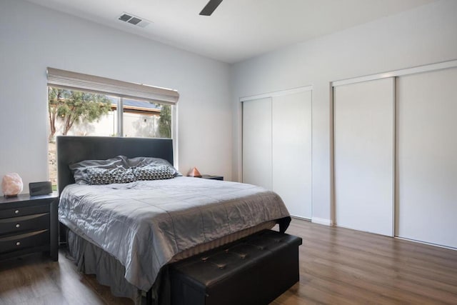 bedroom with multiple closets, ceiling fan, and dark hardwood / wood-style flooring