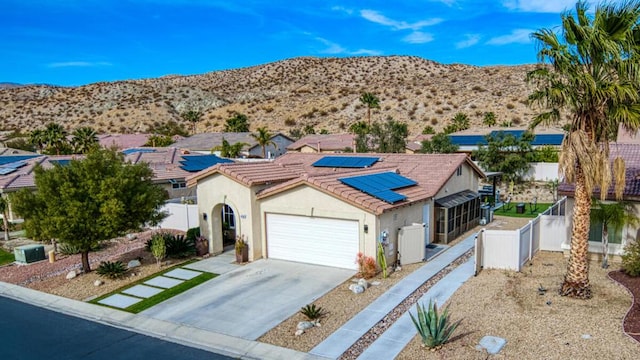 view of front facade with a garage, a mountain view, and solar panels