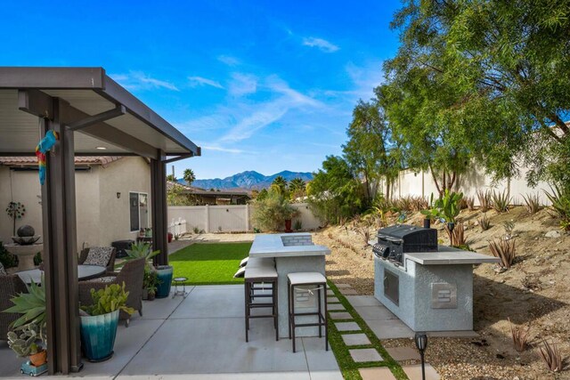 view of patio / terrace featuring a mountain view, an outdoor kitchen, a grill, and exterior bar