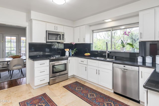 kitchen with dark countertops, decorative backsplash, stainless steel appliances, and a sink