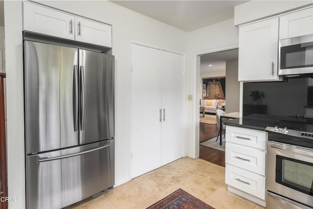 kitchen with stainless steel appliances, dark countertops, white cabinetry, and light tile patterned floors