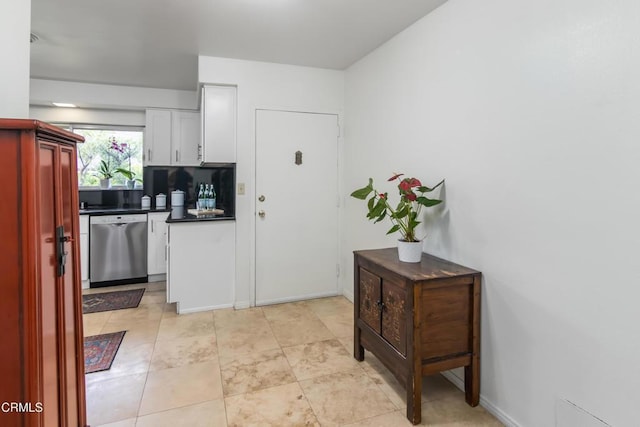 kitchen with dishwasher, dark countertops, baseboards, and white cabinets