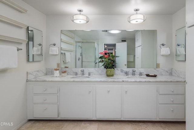 full bath featuring double vanity, a sink, and a shower stall