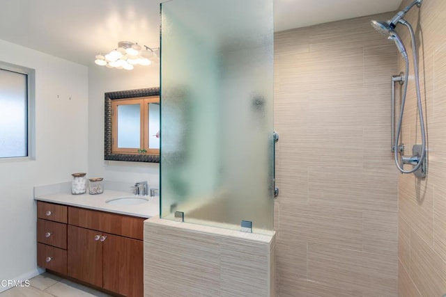 bathroom with tile patterned flooring, a tile shower, and vanity