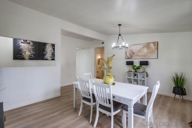 dining space with hardwood / wood-style flooring, lofted ceiling, and an inviting chandelier