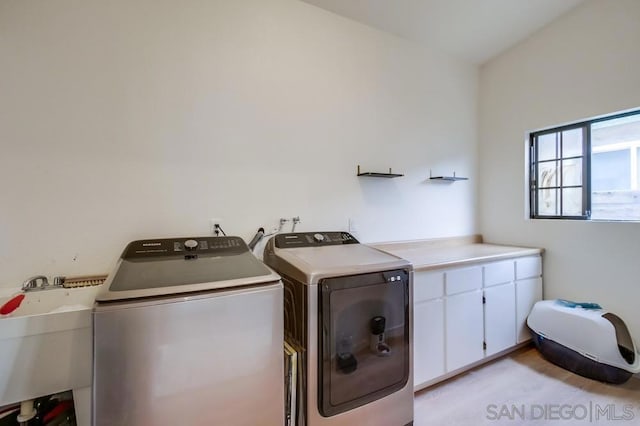 clothes washing area featuring cabinets, sink, and independent washer and dryer