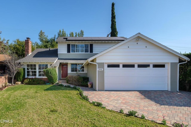 view of property with a garage, a front yard, and solar panels