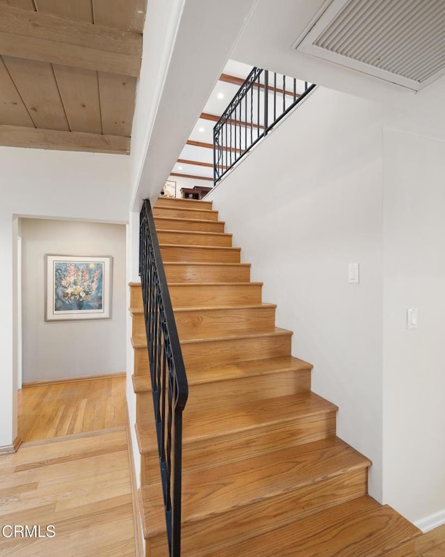 stairs featuring beamed ceiling, hardwood / wood-style floors, and wooden ceiling