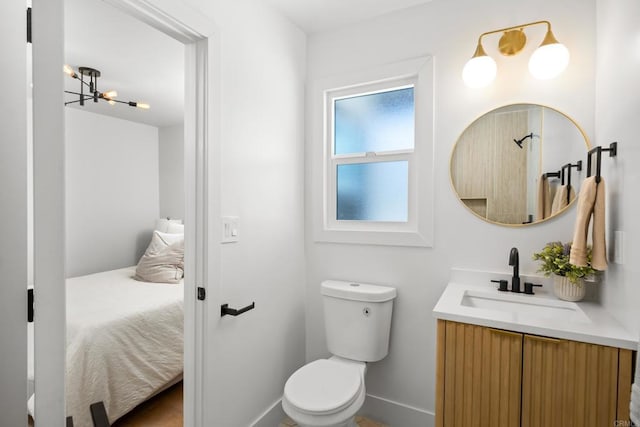 bathroom with an inviting chandelier, vanity, and toilet