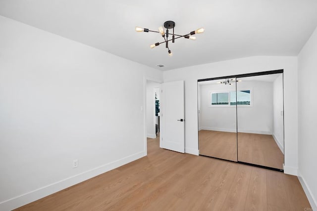 unfurnished bedroom with a notable chandelier, a closet, and light wood-type flooring