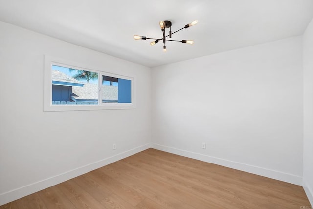 spare room with a notable chandelier and hardwood / wood-style flooring