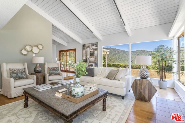 sunroom featuring a mountain view, track lighting, and lofted ceiling with beams