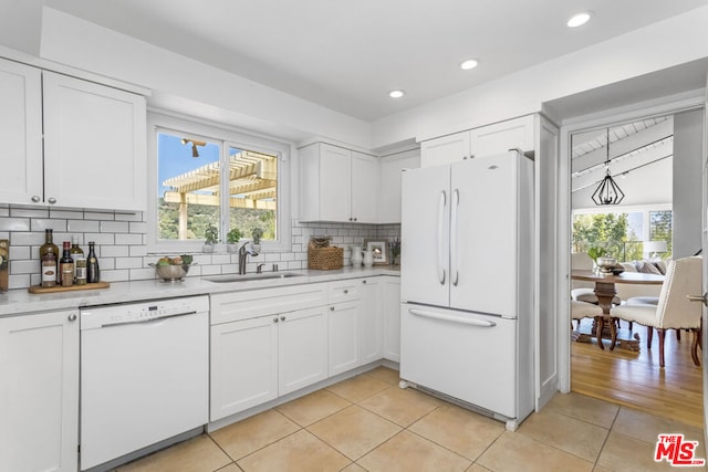 kitchen with white cabinetry, sink, backsplash, light tile patterned floors, and white appliances