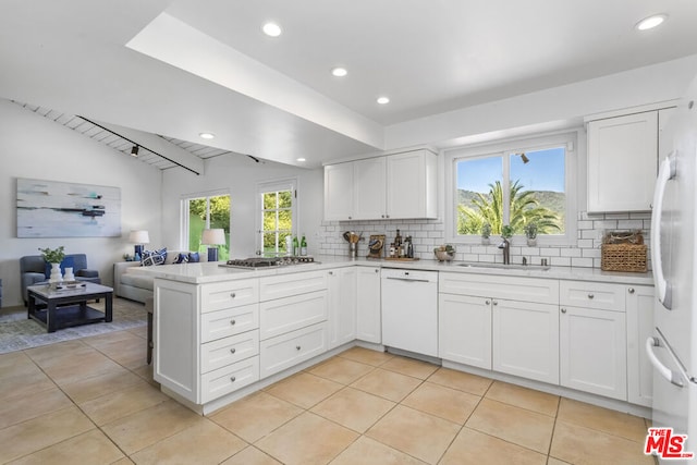 kitchen with sink, backsplash, white cabinets, and white appliances