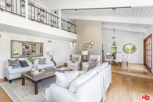 living room featuring beamed ceiling, high vaulted ceiling, and light hardwood / wood-style flooring