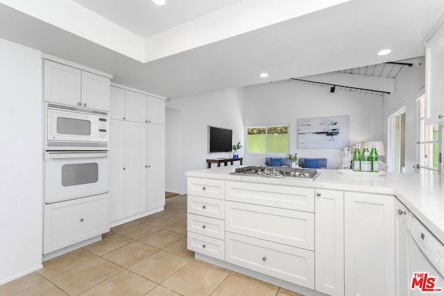 kitchen featuring light tile patterned floors, white cabinets, and white appliances