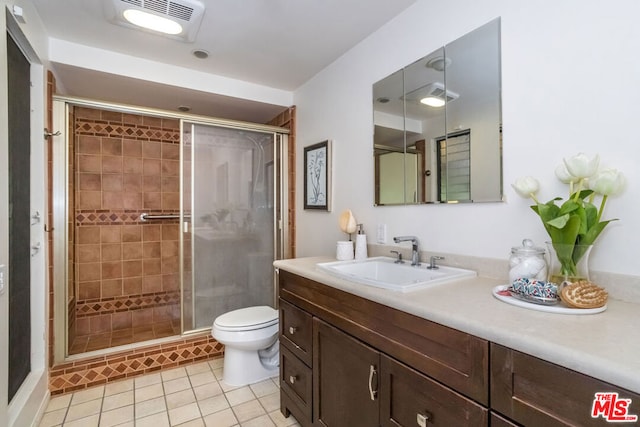 bathroom with vanity, toilet, a shower with shower door, and tile patterned flooring