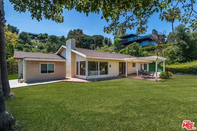 rear view of property featuring a yard, a pergola, and a patio