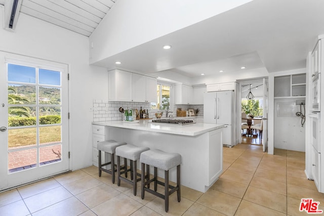 kitchen featuring white refrigerator, white cabinetry, a kitchen breakfast bar, and kitchen peninsula