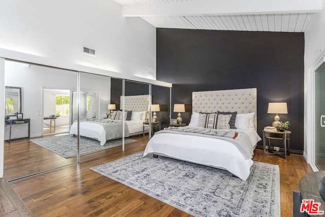 bedroom featuring high vaulted ceiling, hardwood / wood-style floors, and beam ceiling