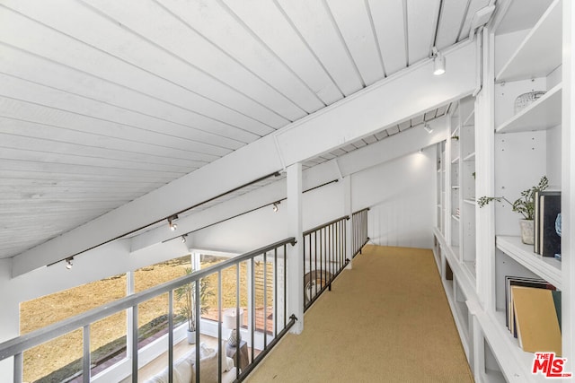 hall featuring light colored carpet, rail lighting, and wooden ceiling