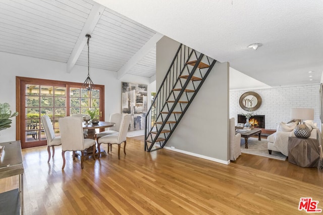 dining space with a brick fireplace, wood ceiling, hardwood / wood-style floors, and beamed ceiling