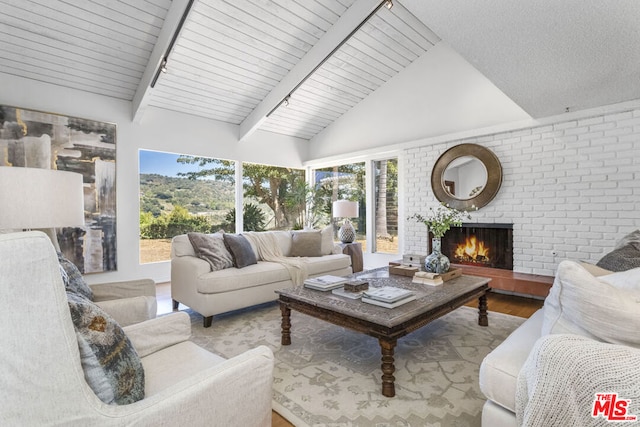 living room with high vaulted ceiling, a fireplace, light hardwood / wood-style floors, and beamed ceiling