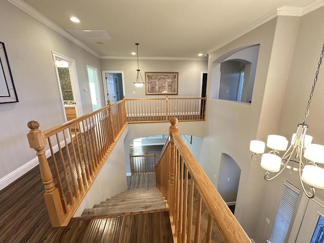 staircase featuring crown molding, an inviting chandelier, and hardwood / wood-style flooring