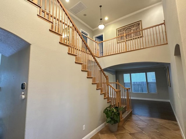 stairs featuring tile patterned flooring, crown molding, and a towering ceiling