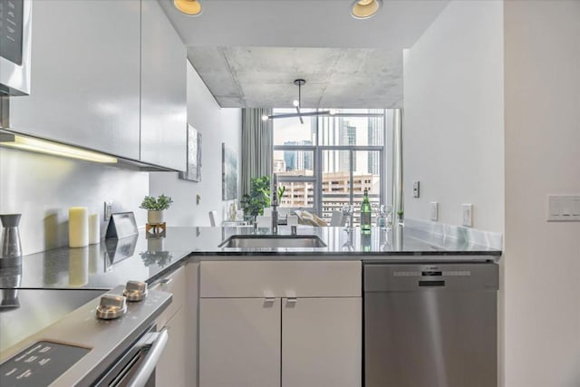 kitchen featuring stainless steel appliances, sink, white cabinets, and kitchen peninsula