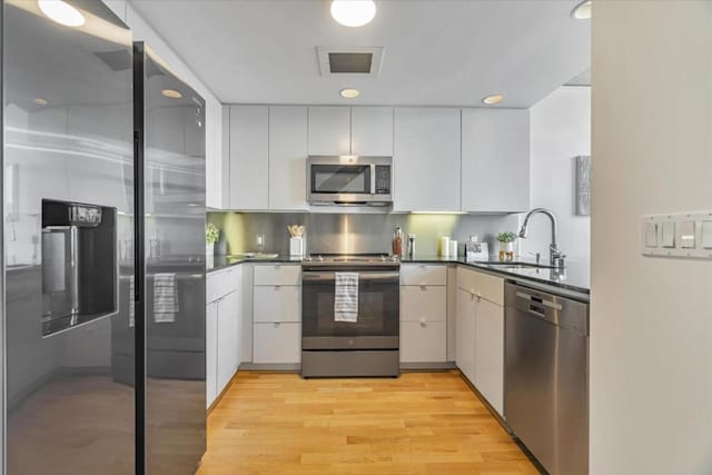 kitchen with stainless steel appliances, white cabinetry, and sink