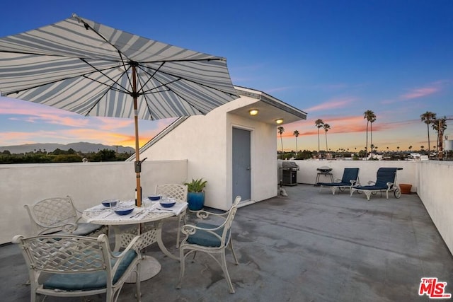 patio terrace at dusk featuring a grill