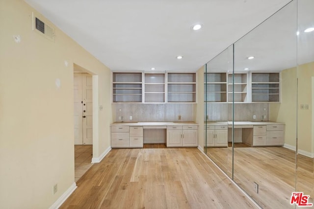 kitchen with tasteful backsplash, built in desk, and light wood-type flooring