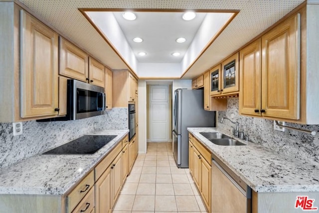 kitchen with light stone counters, light tile patterned floors, sink, and black appliances