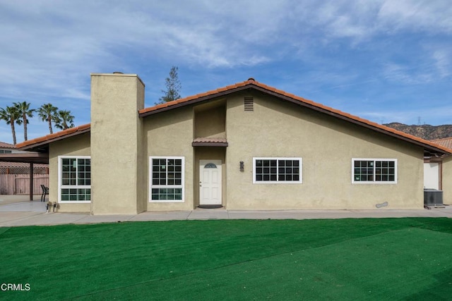 rear view of property featuring central AC and a lawn