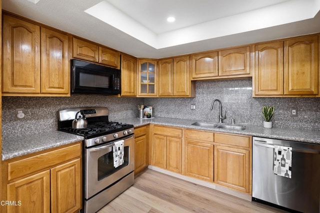 kitchen with sink, light hardwood / wood-style flooring, appliances with stainless steel finishes, backsplash, and a raised ceiling